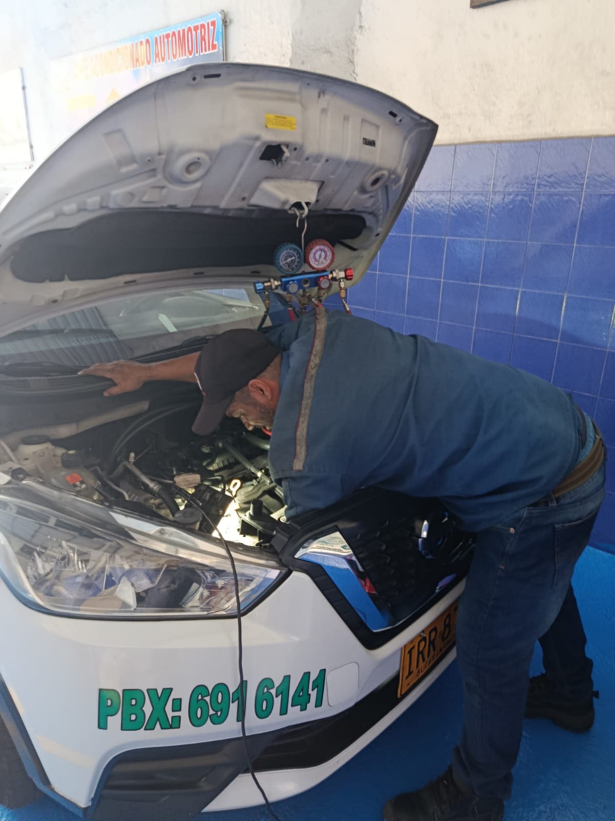 Técnico de Servirefriauto revisando el aire acondicionado con manómetros